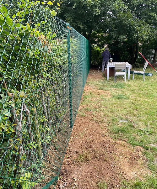 Photo d'une dame dans son jardin avec une clôture installée par Sylvain Leroy