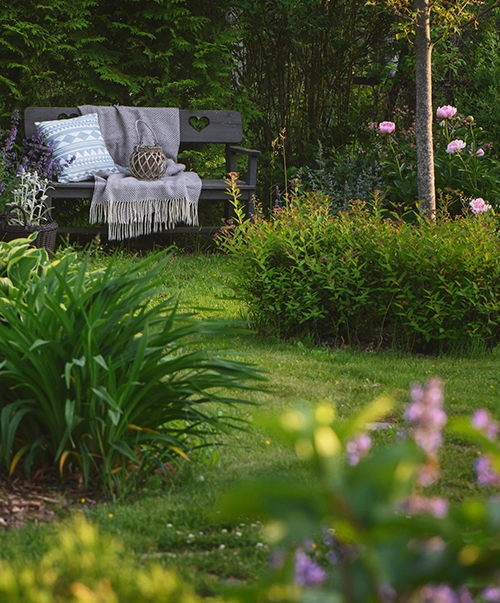 Photo d'un jardin fleurit avec un banc en bois et des couvertures
